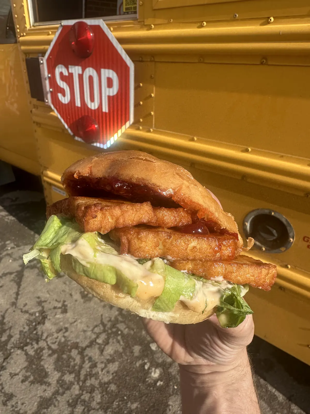 A crispy chicken burger from Burger Bus next to the bus stop sign