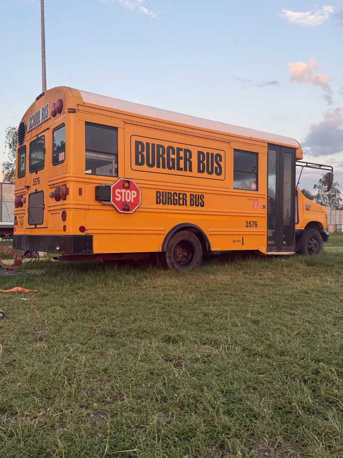 Burger Bus, a yellow American school bus, parked in a field at sunset