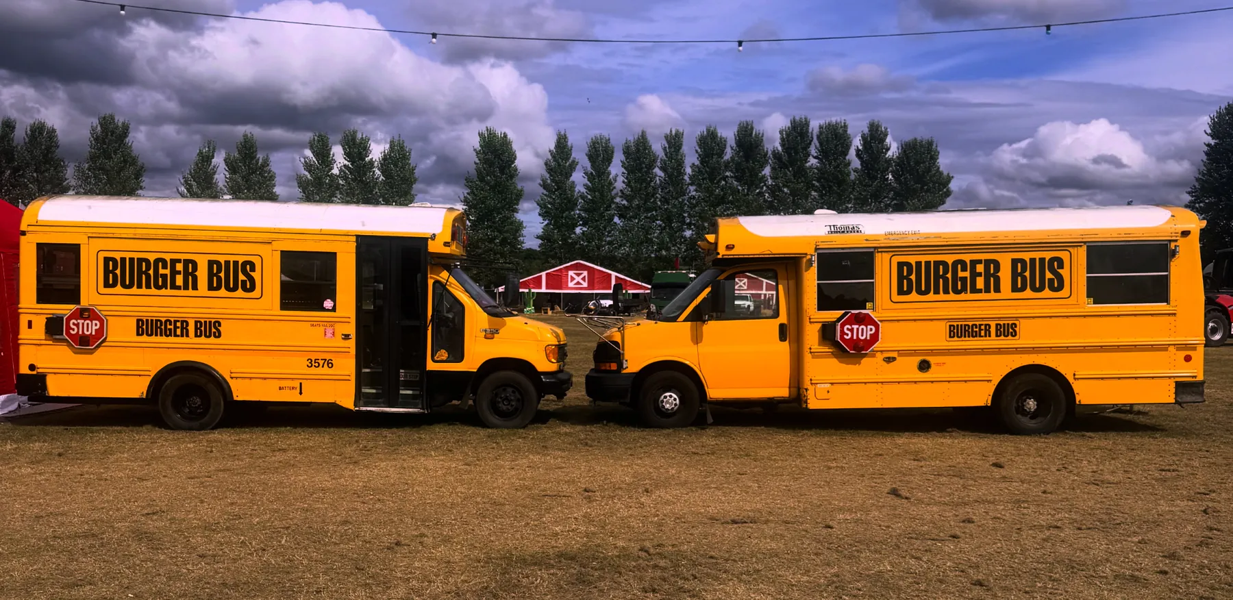 Two Burger Bus food trucks, converted yellow American school buses, parked nose to nose at a South West event