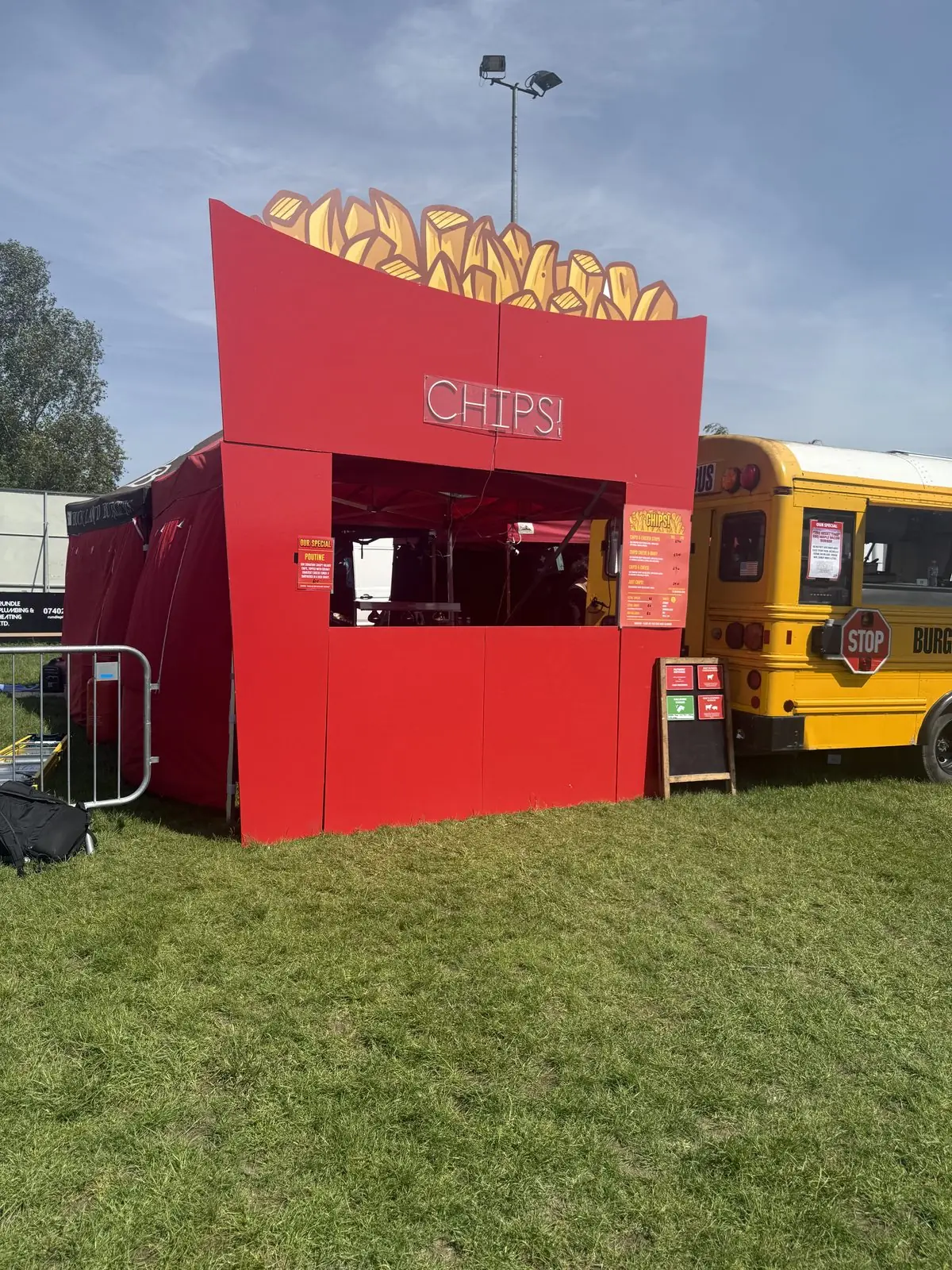 The CHIPS! stall — a giant red chip box with a neon CHIPS! sign — set up at an outdoor event next to Burger Bus